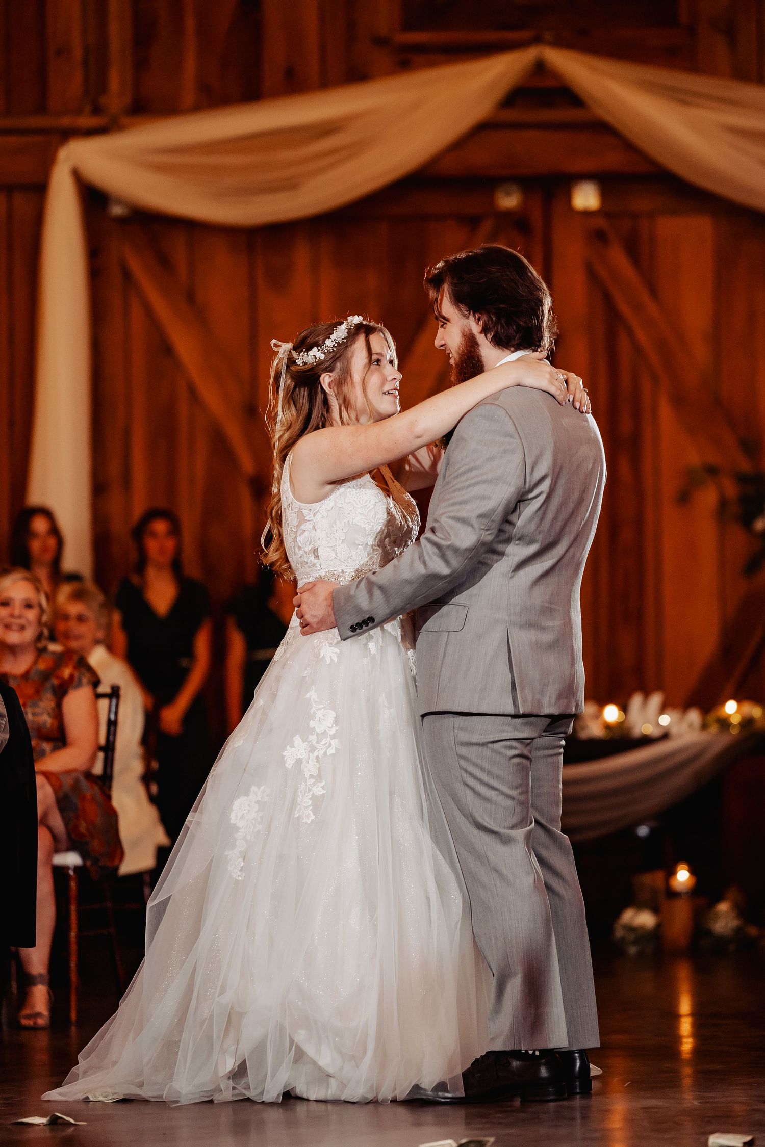Romantic first dance at rustic barn wedding with draped fabric decor and warm lighting.