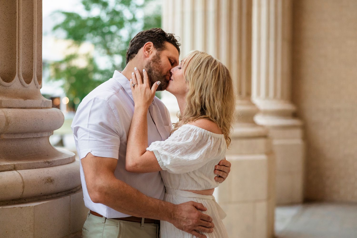 Couple embracing near classical architecture column during a romantic photoshoot.