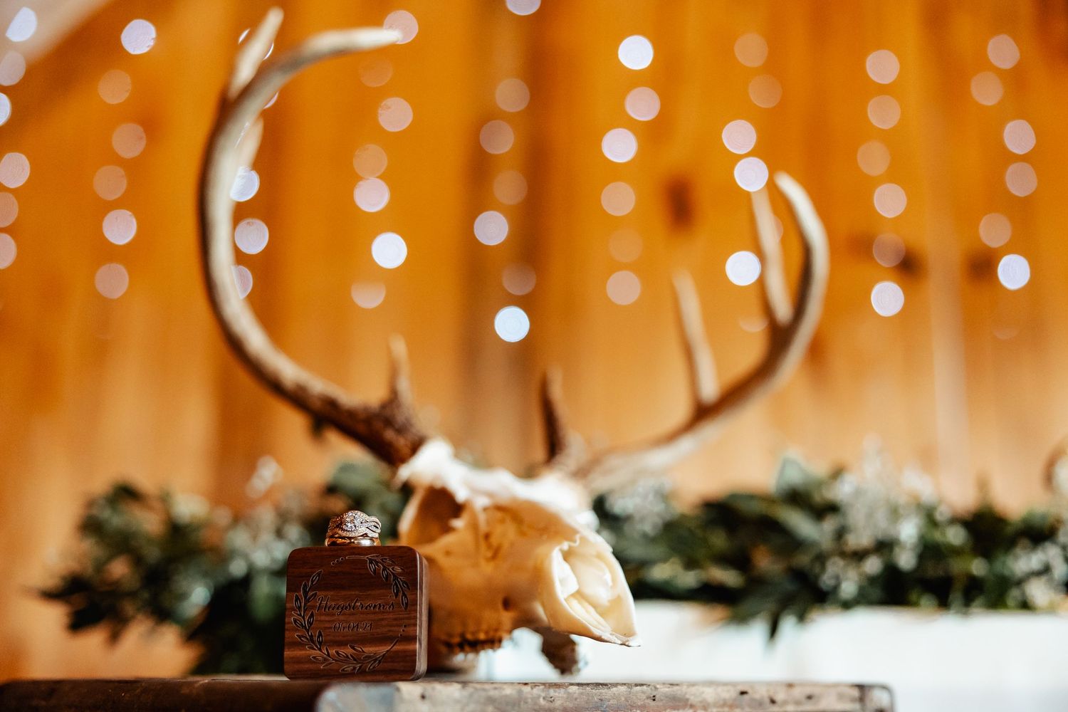 Artistic wedding detail shot of deer skull and perfume bottle against bokeh light background.