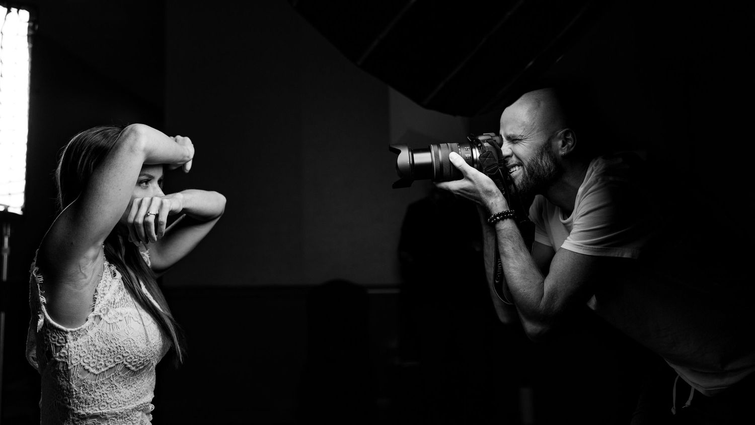 Black and white studio photography session with photographer and subject in dramatic lighting.