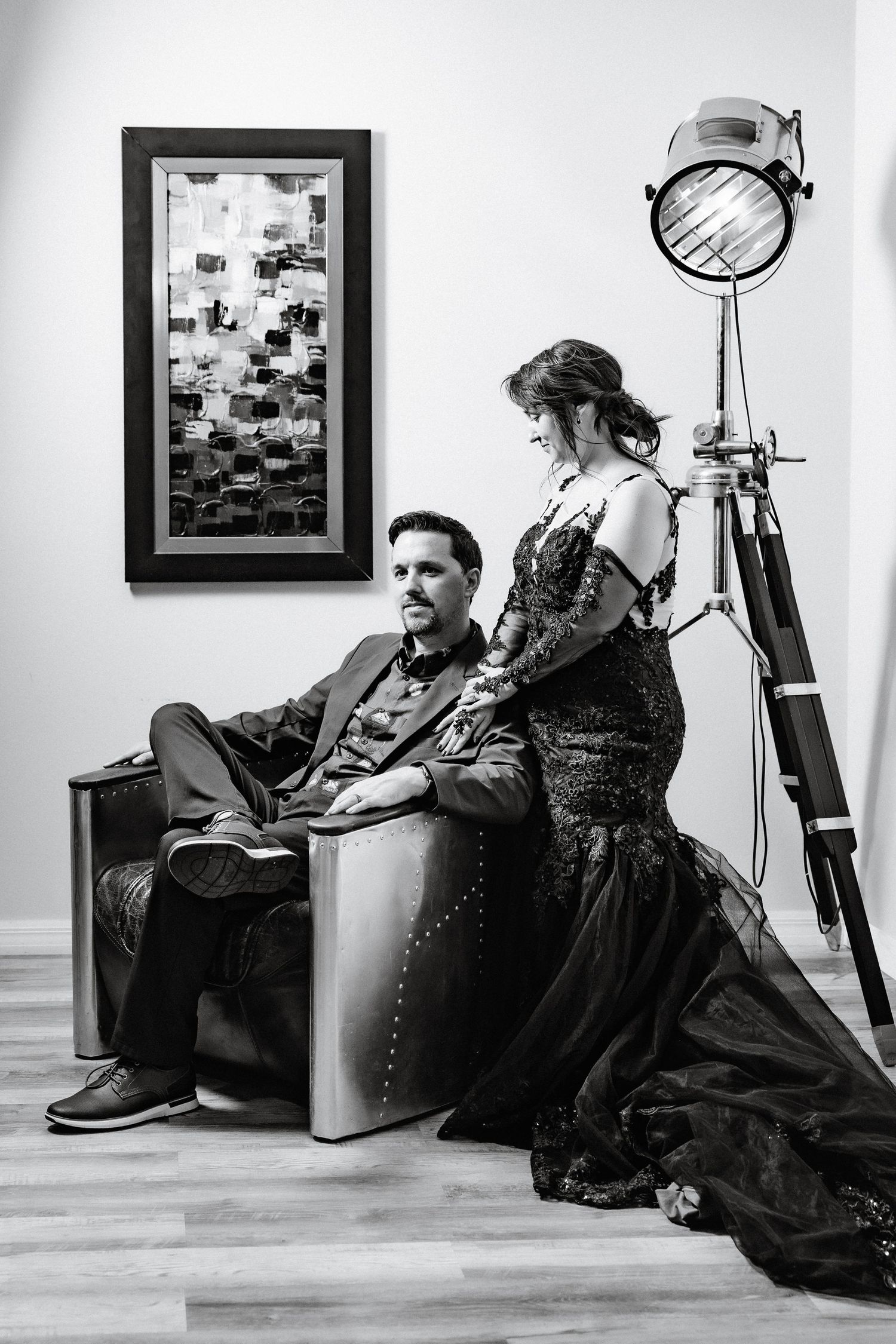 Black and white portrait of couple posing with vintage film light, woman in black gown, man in suit.