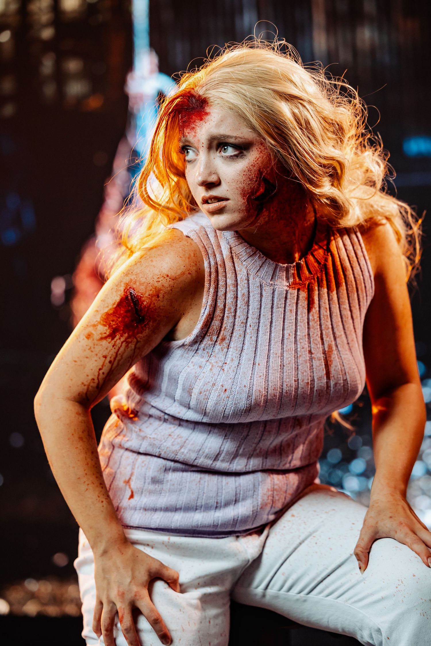Dramatic portrait with blood effects and moody lighting in gray sleeveless top.