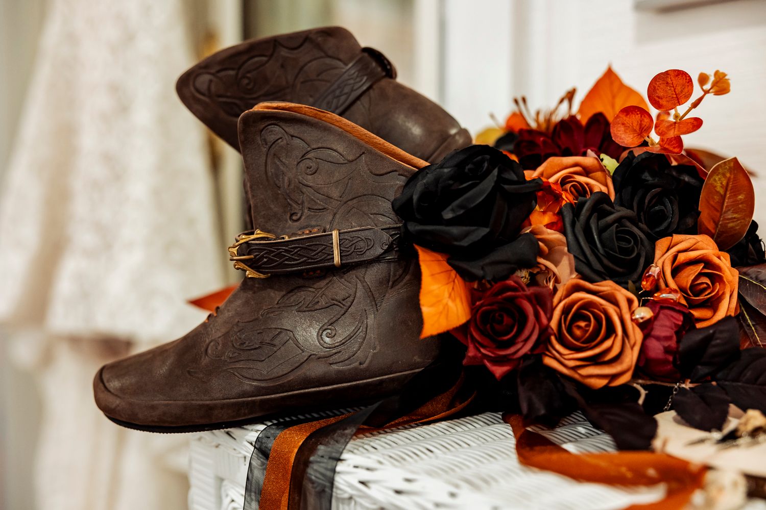 Vintage brown leather boots displayed with black and orange roses in an autumn-themed wedding setting.