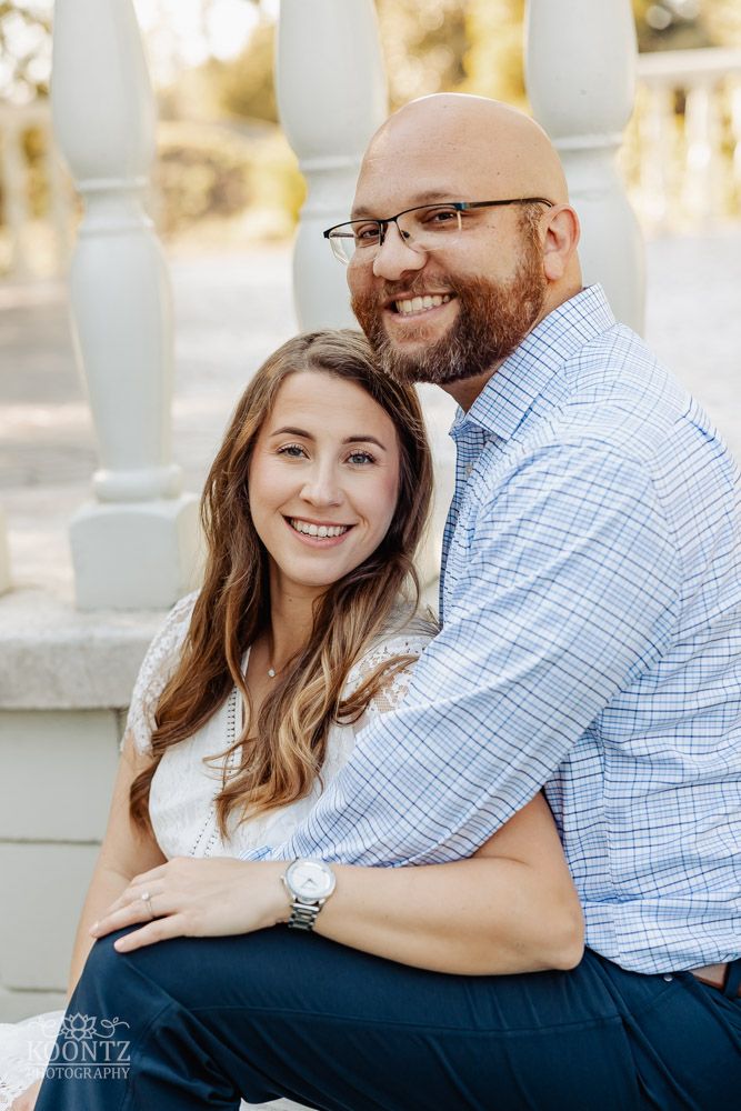 A happy couple poses together on white steps during an outdoor photo session.