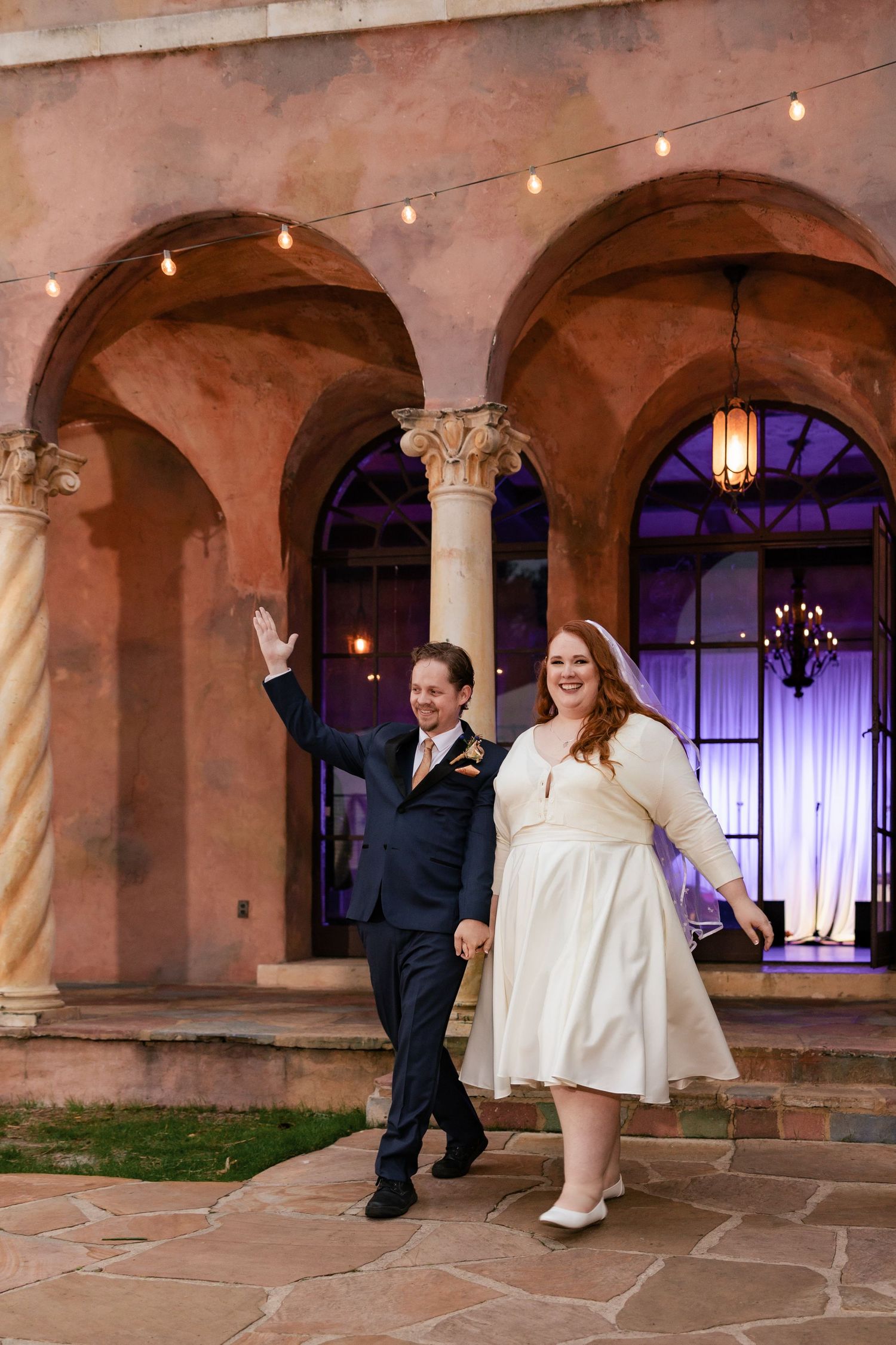 Smiling bride and groom making grand entrance at outdoor wedding reception.