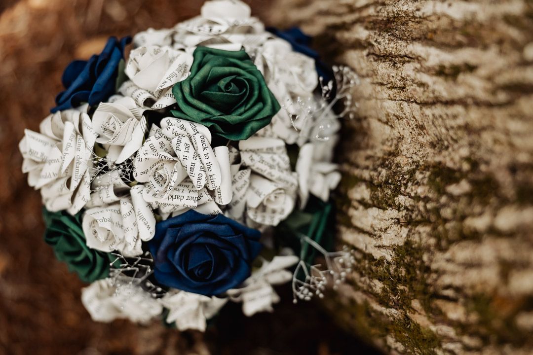 Wedding bouquet made of white and blue paper roses against rustic wood texture.
