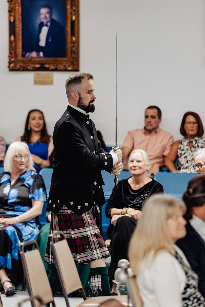 A person in traditional Scottish dress performs with a sword for an audience.