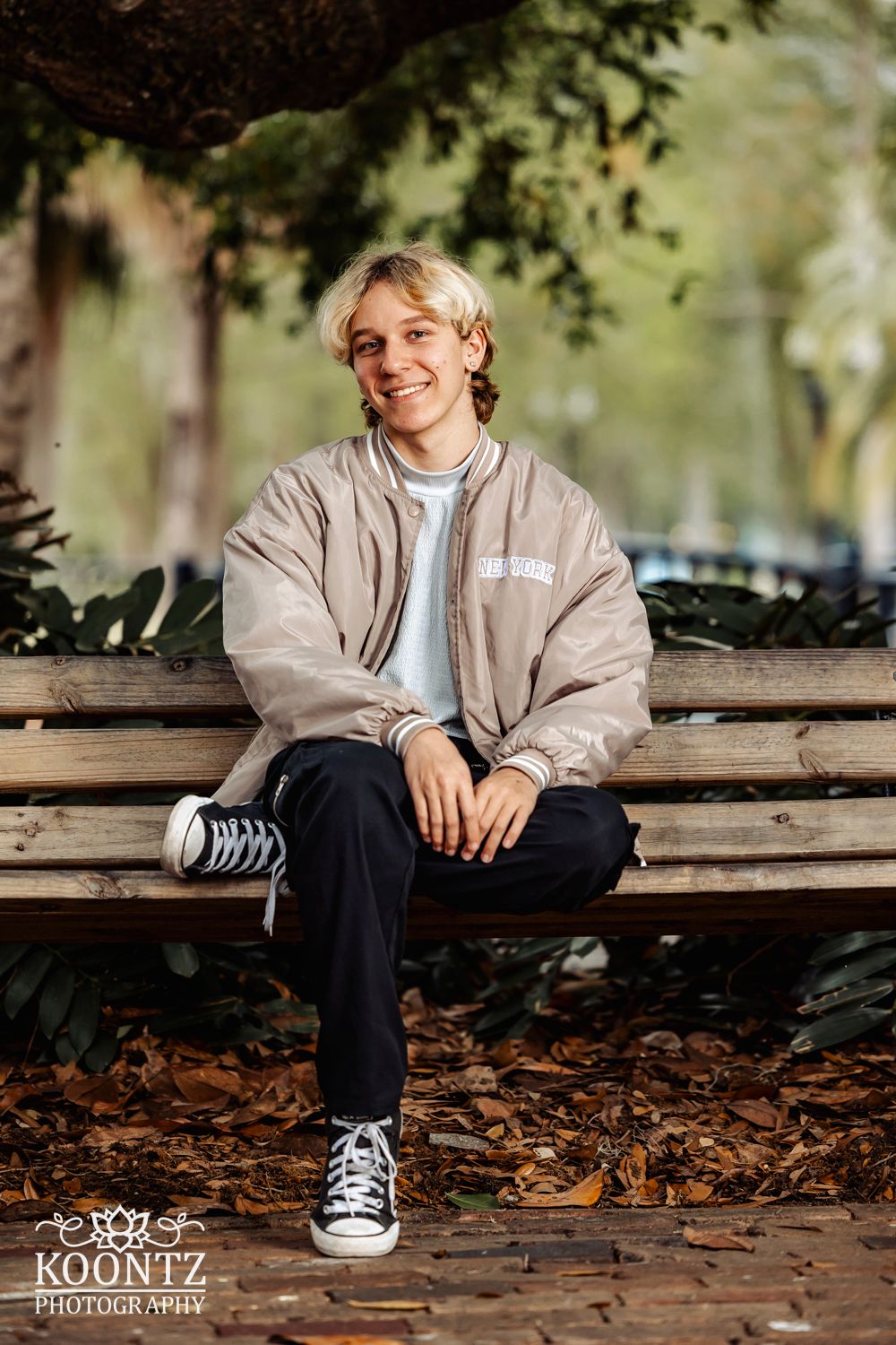 Relaxed outdoor portrait on a park bench surrounded by fall scenery.