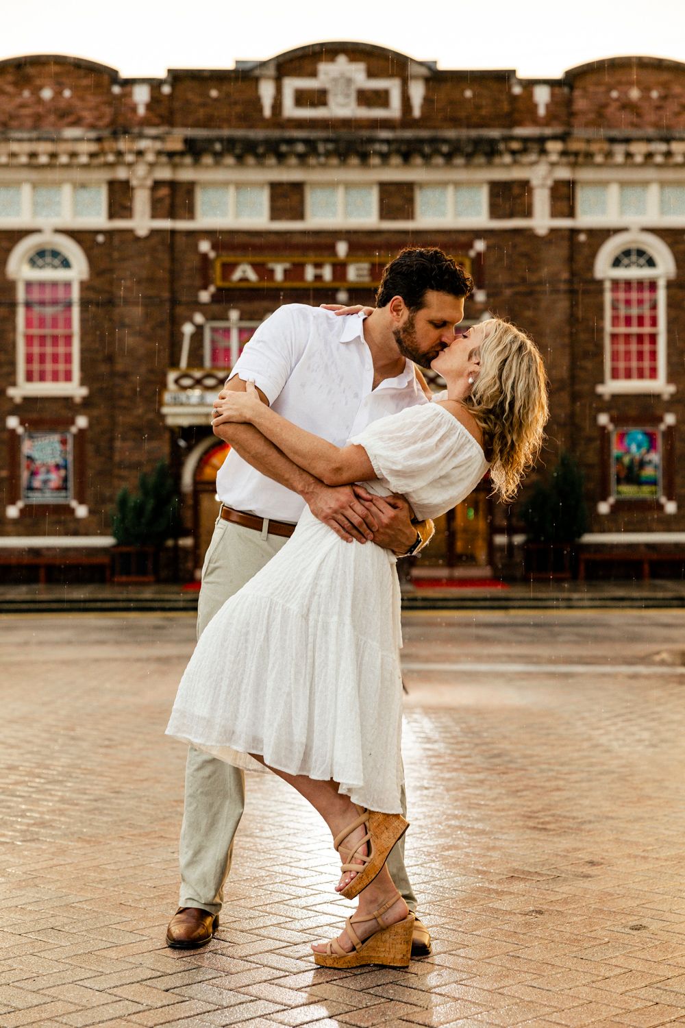 Romantic dip pose in front of historic brick building during engagement session.