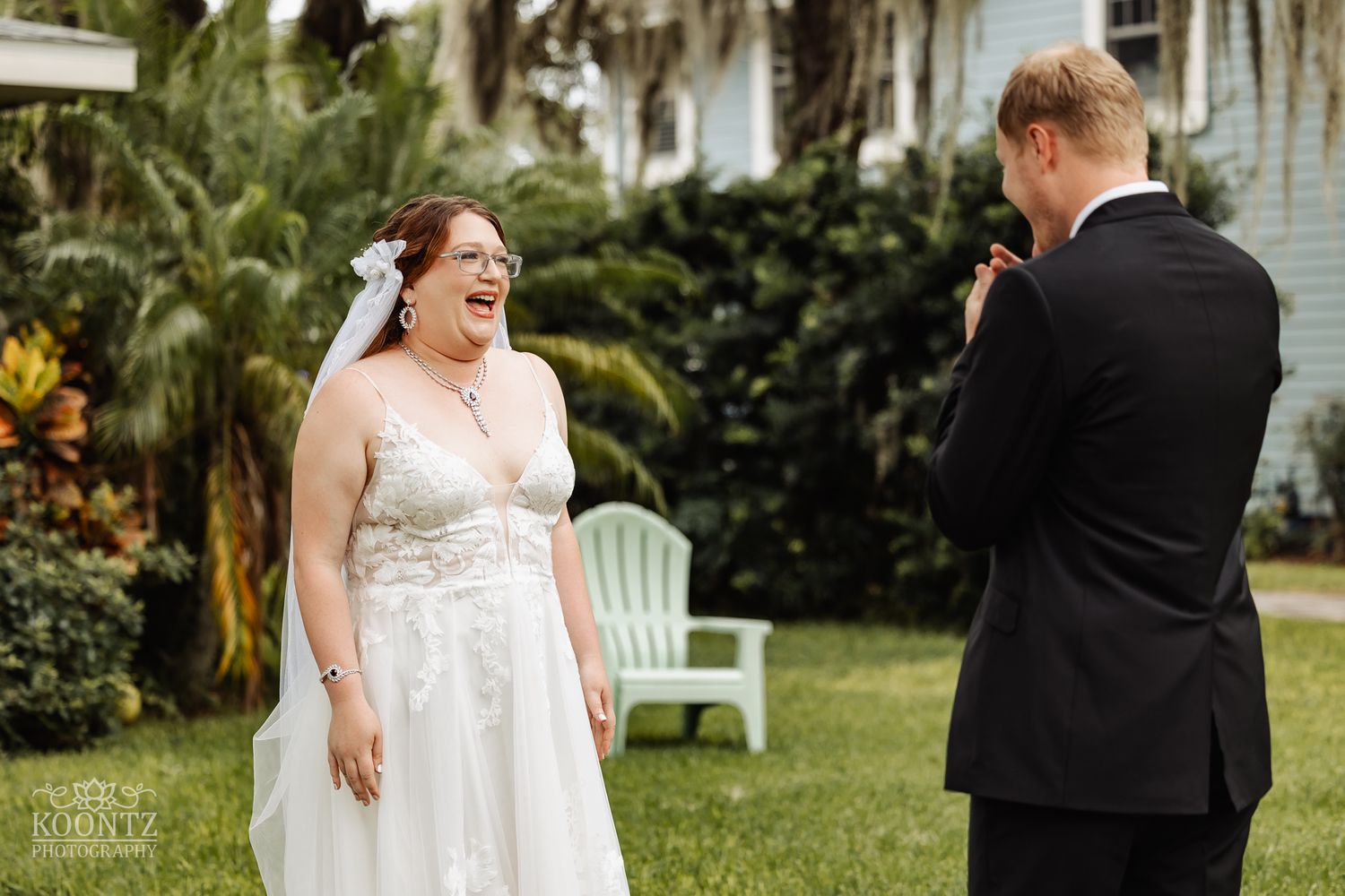 An emotional first look moment between newlyweds in a lush tropical garden setting.