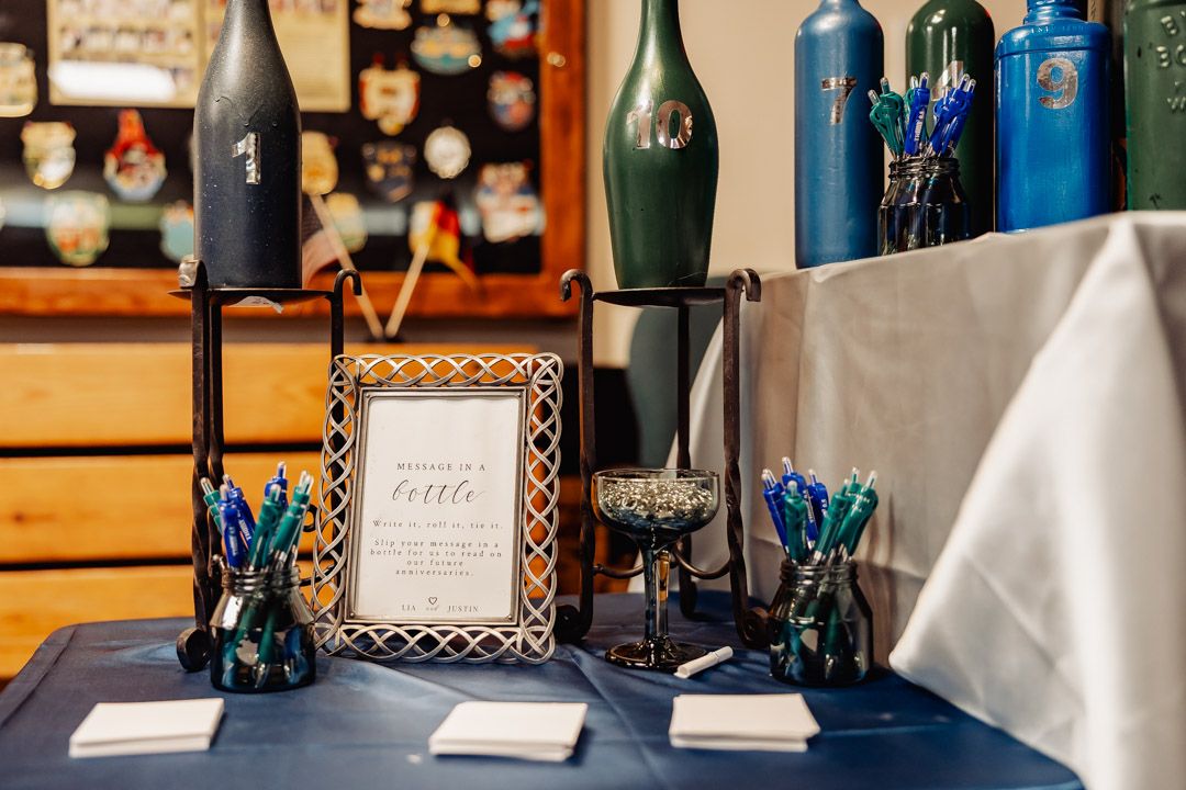 Wedding reception table setup with blue decorations and vintage wine bottles.