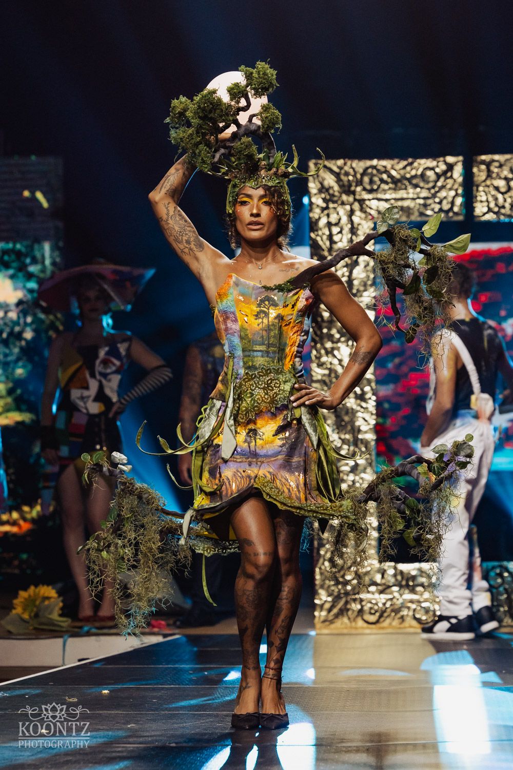 Fashion model walks runway in avant-garde dress made from recycled materials and natural elements during eco fashion show.
