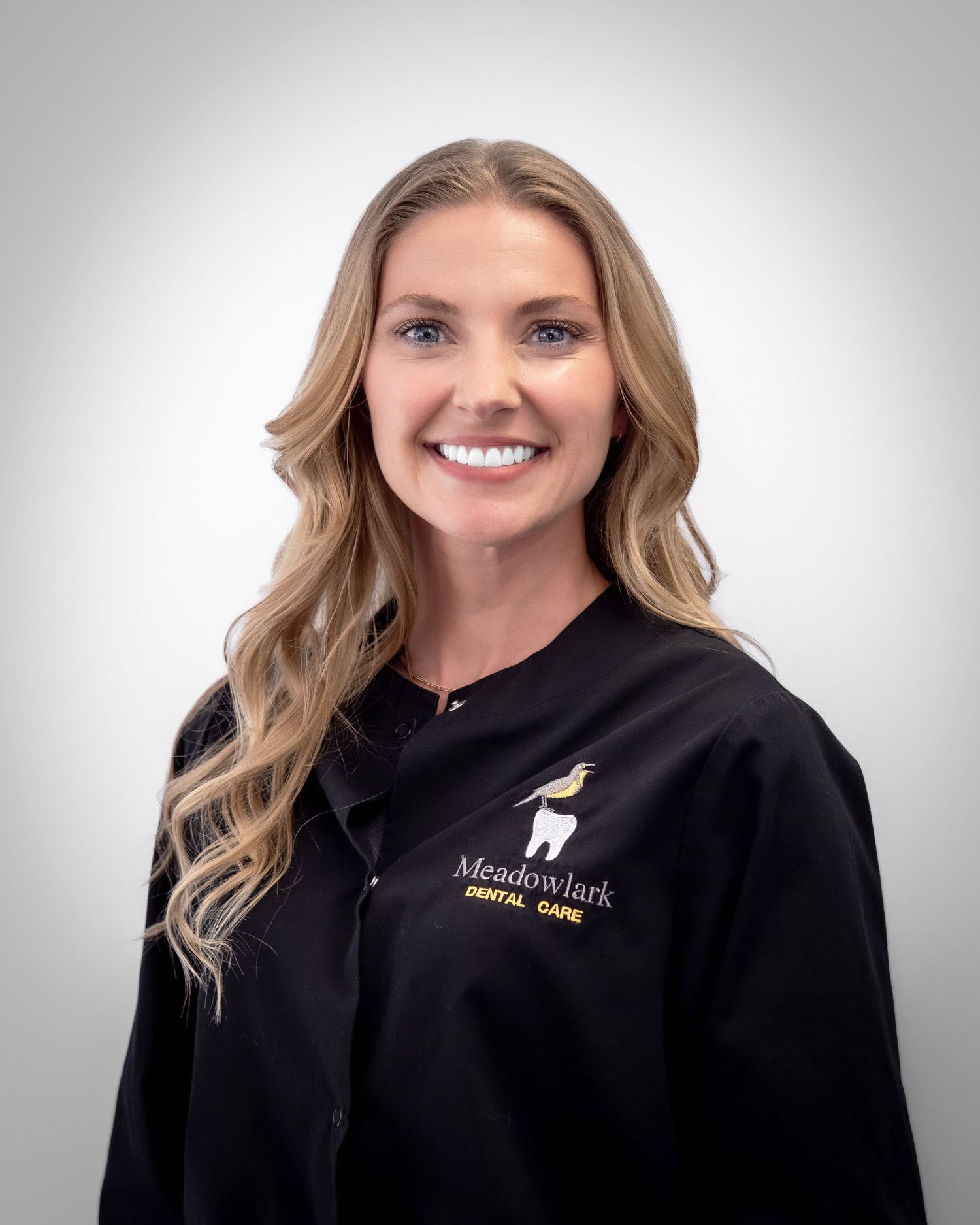 Meadowlark Dental Care team member smiling in black uniform, professional headshot photo.