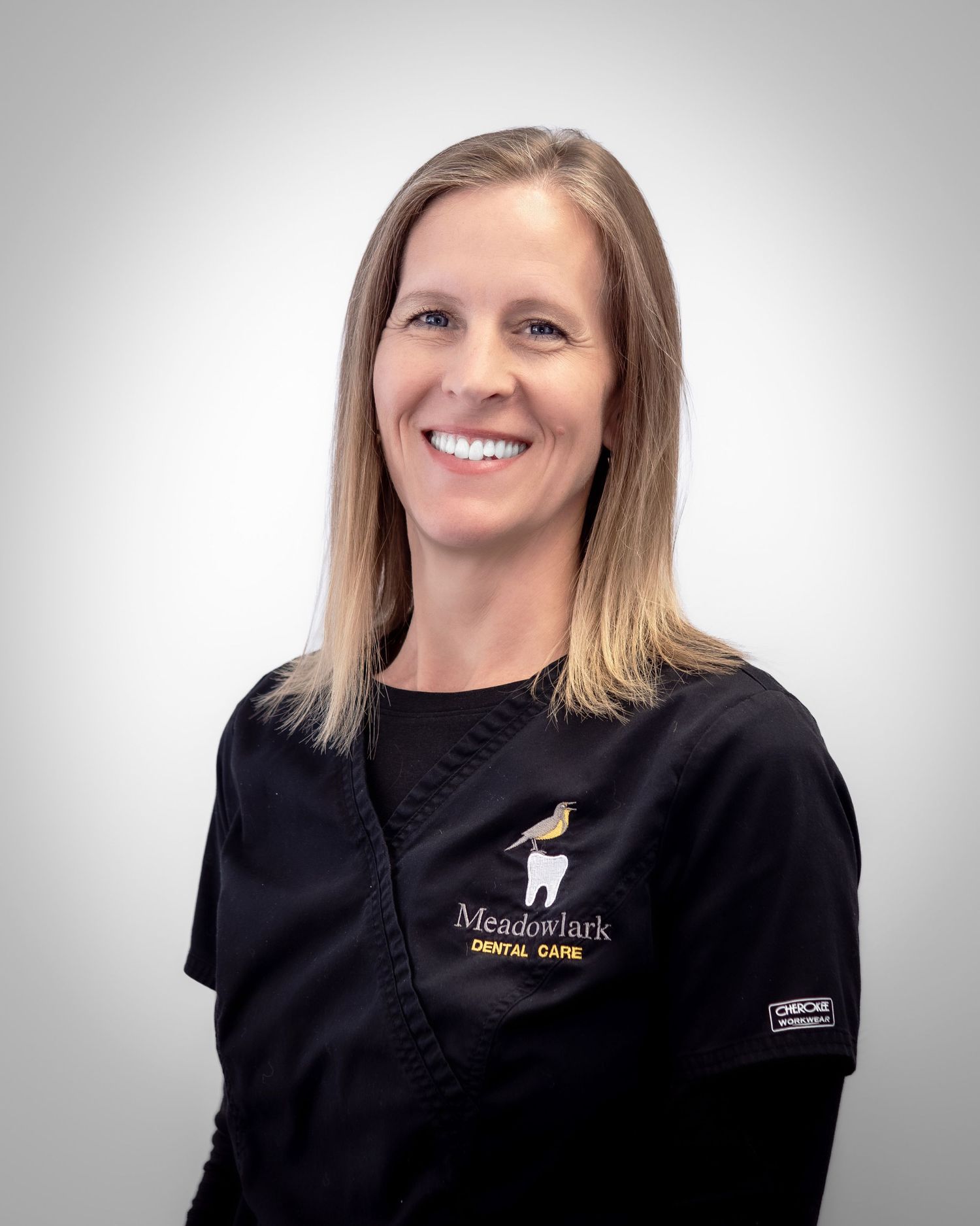 Meadowlark Dental Care staff member smiling in black scrubs, professional headshot photo.