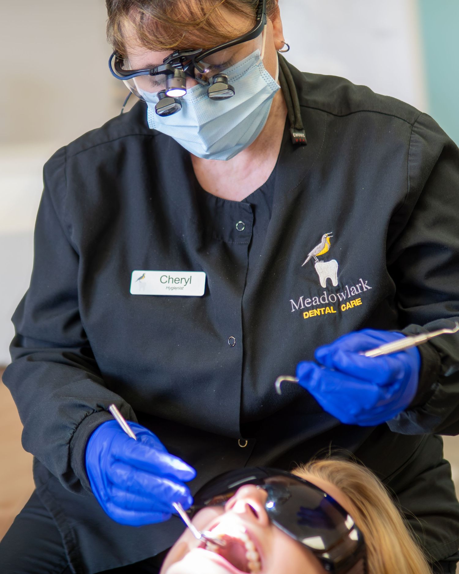 Meadowlark Dental Care hygienist Cheryl performs a dental exam on a patient wearing protective eyewear.