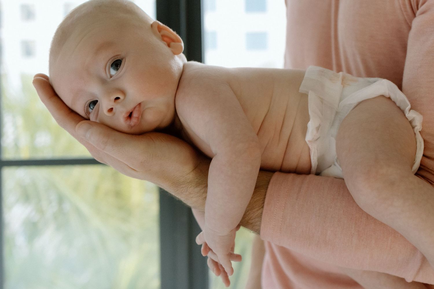 Mother holding her newborn during a relaxed in-home newborn photography session.
