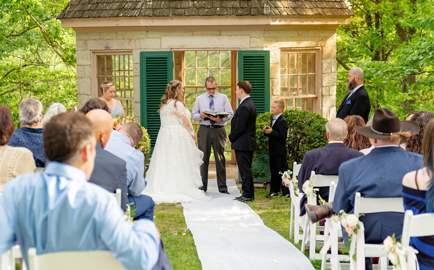 Outdoor wedding ceremony with bride and groom at altar before seated guests. Taken by Row And Co Photography in FXBG VA