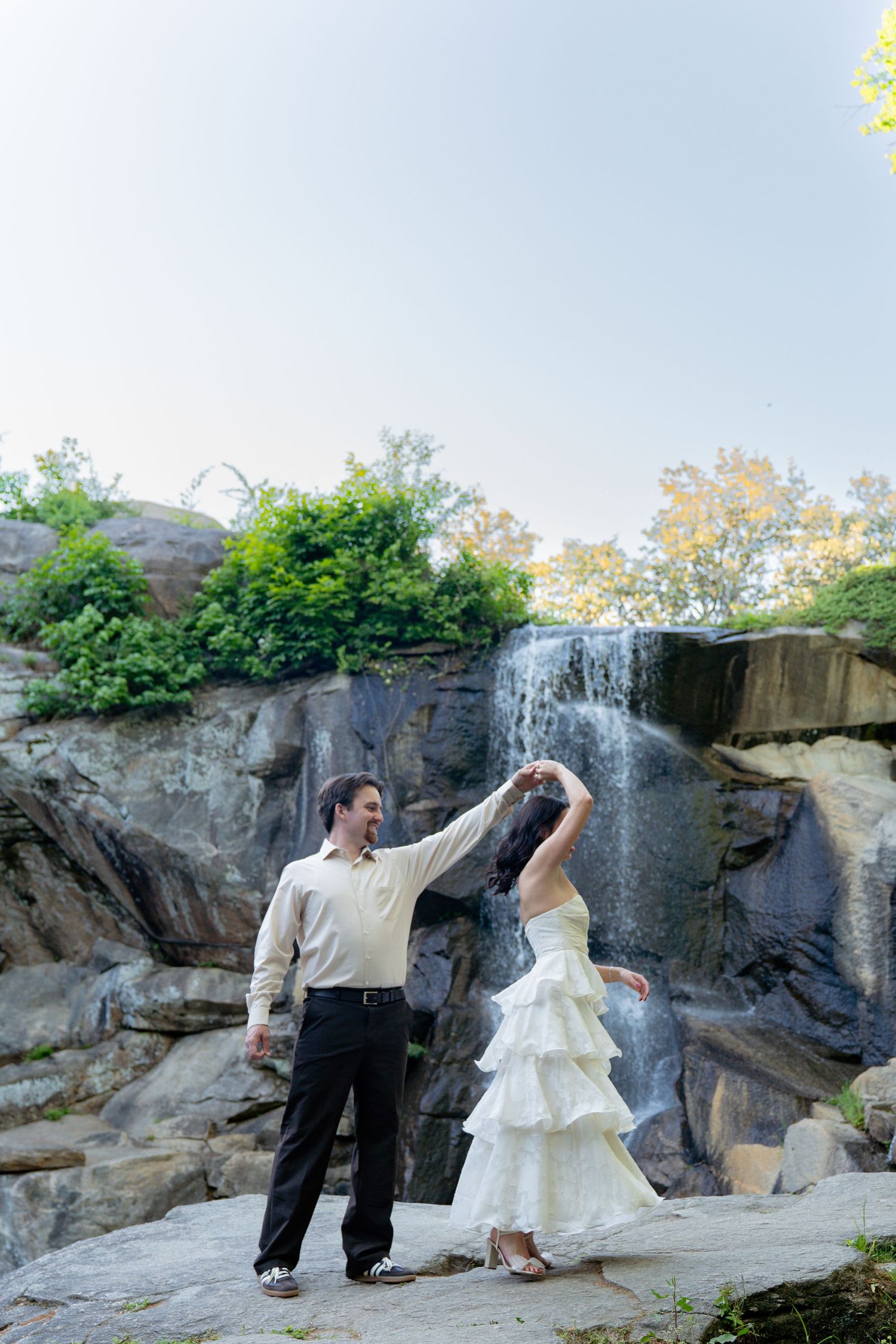 Bride and groom dancing in front of scenic waterfall during outdoor wedding portrait session. Taken by Row And Co Photography in FXBG VA