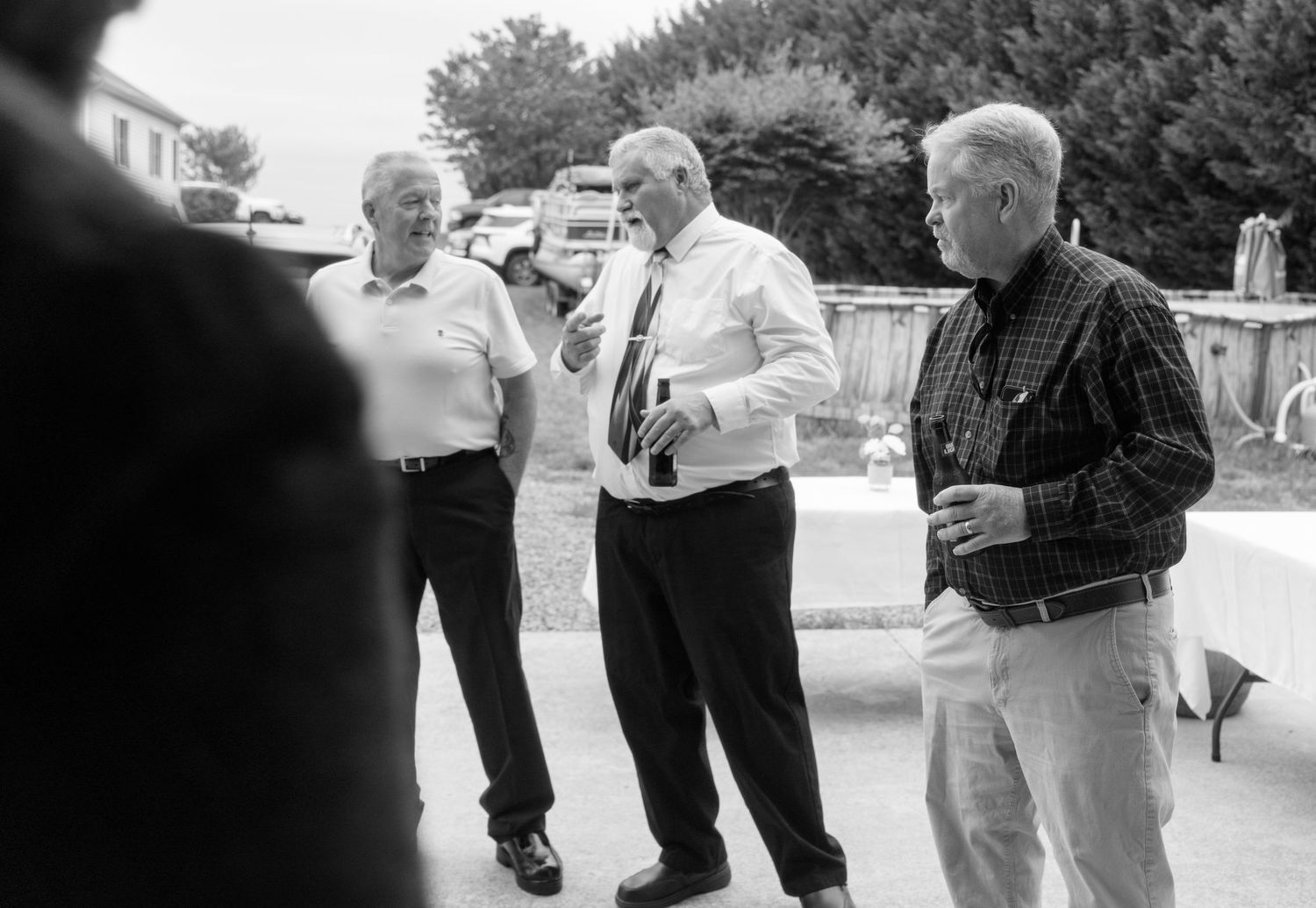 Three men in business casual attire engaged in conversation outdoors at a casual gathering event.