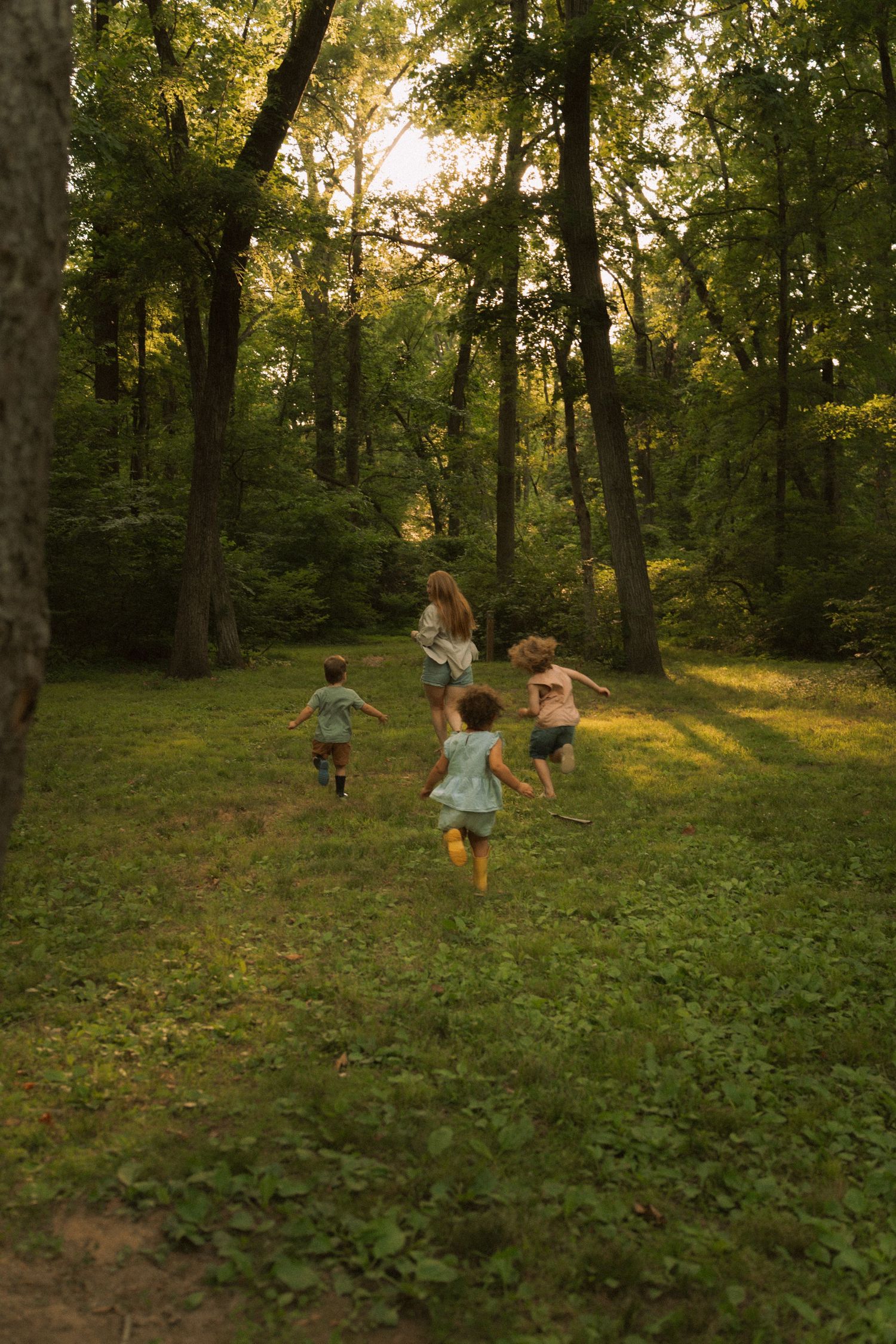 Children running through a lush green forest during golden hour sunset light. Taken by Row And Co Photography in FXBG VA