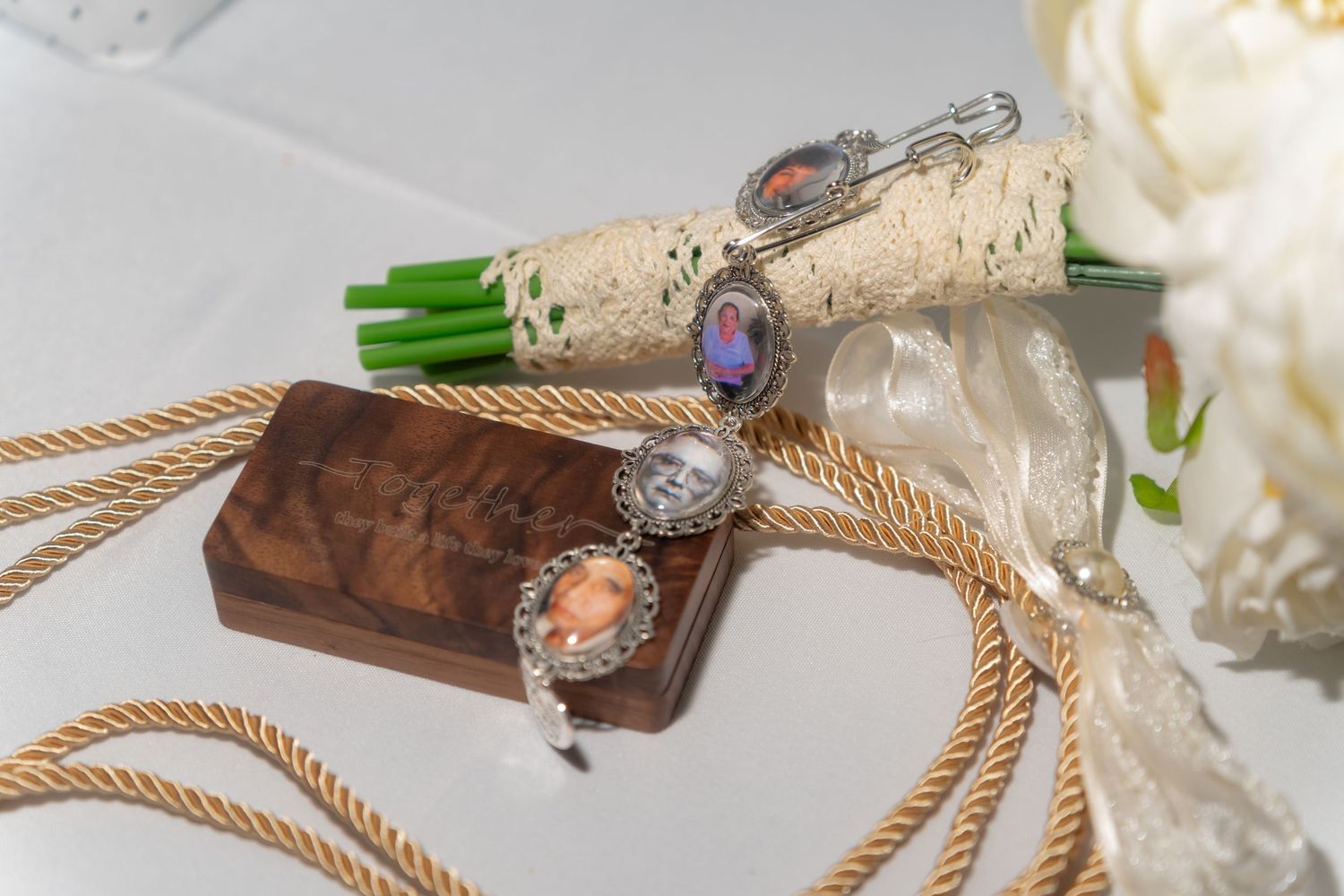 Elegant bracelet with colorful gemstones displayed on wooden box beside rope and white floral bouquet.