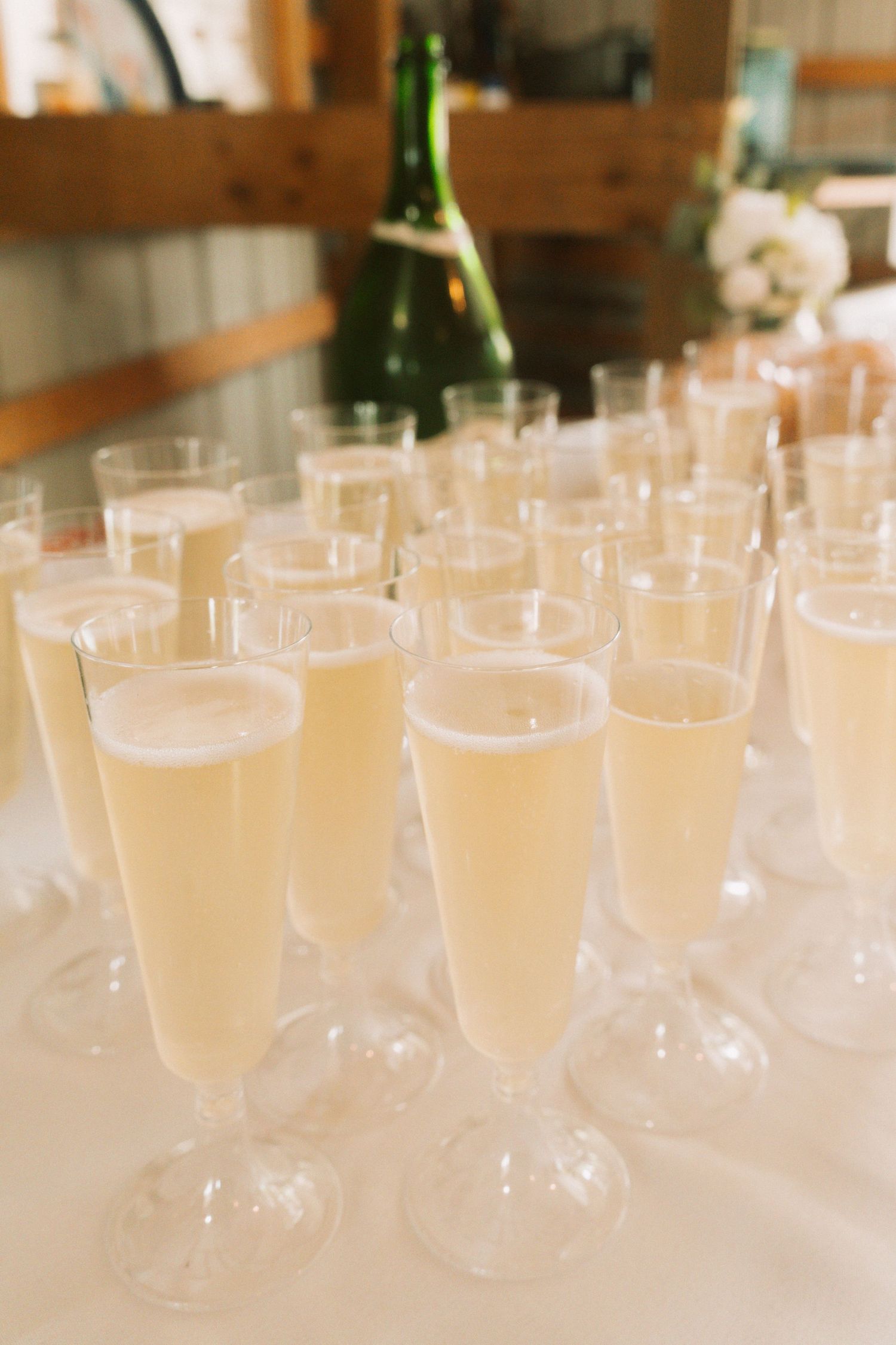 Rows of elegant champagne flutes filled with sparkling wine on a white tablecloth at a wedding reception.