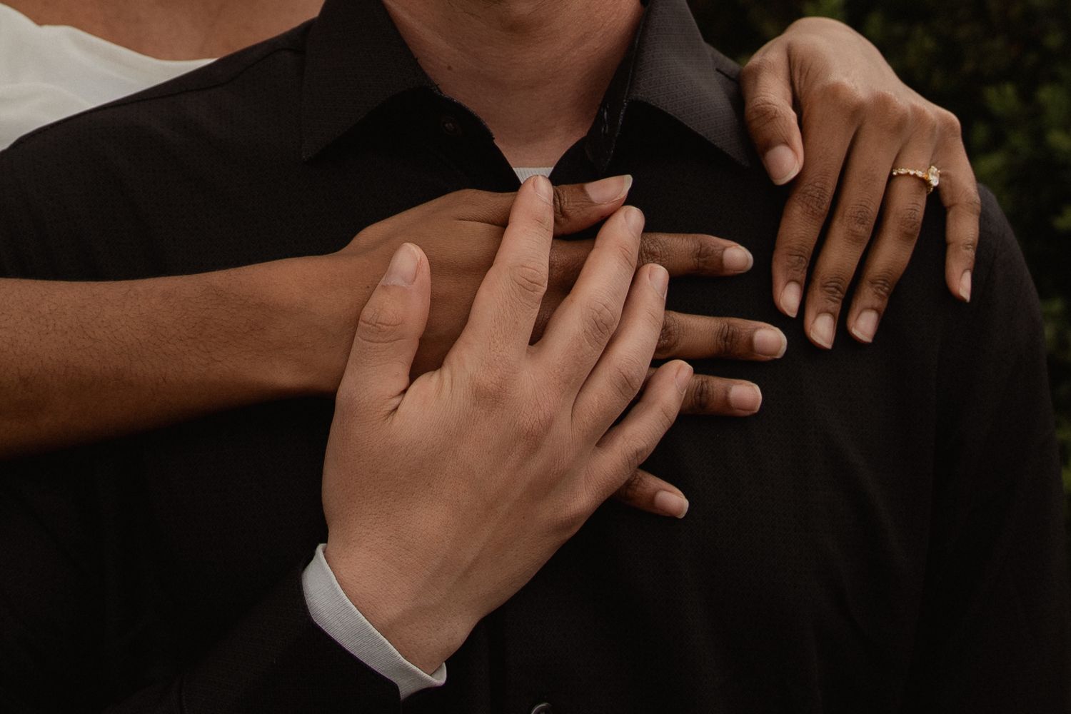 Close-up of couple embracing showing engagement ring on woman's hand. Taken by Row And Co Photography in FXBG VA