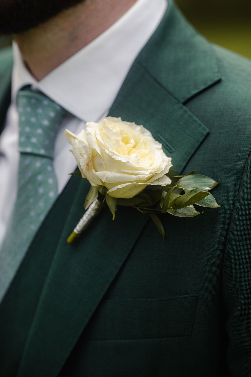 Ansteckblume auf grünem Anzug von Fingerschwur Hochzeiten