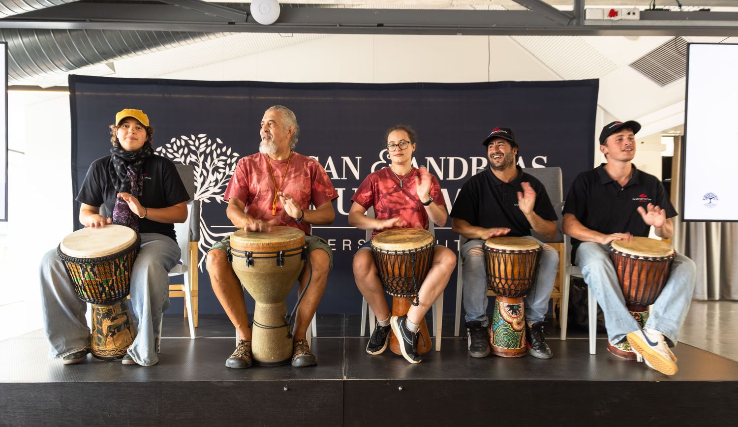 Musicians perform on African drums during a cultural presentation on stage.