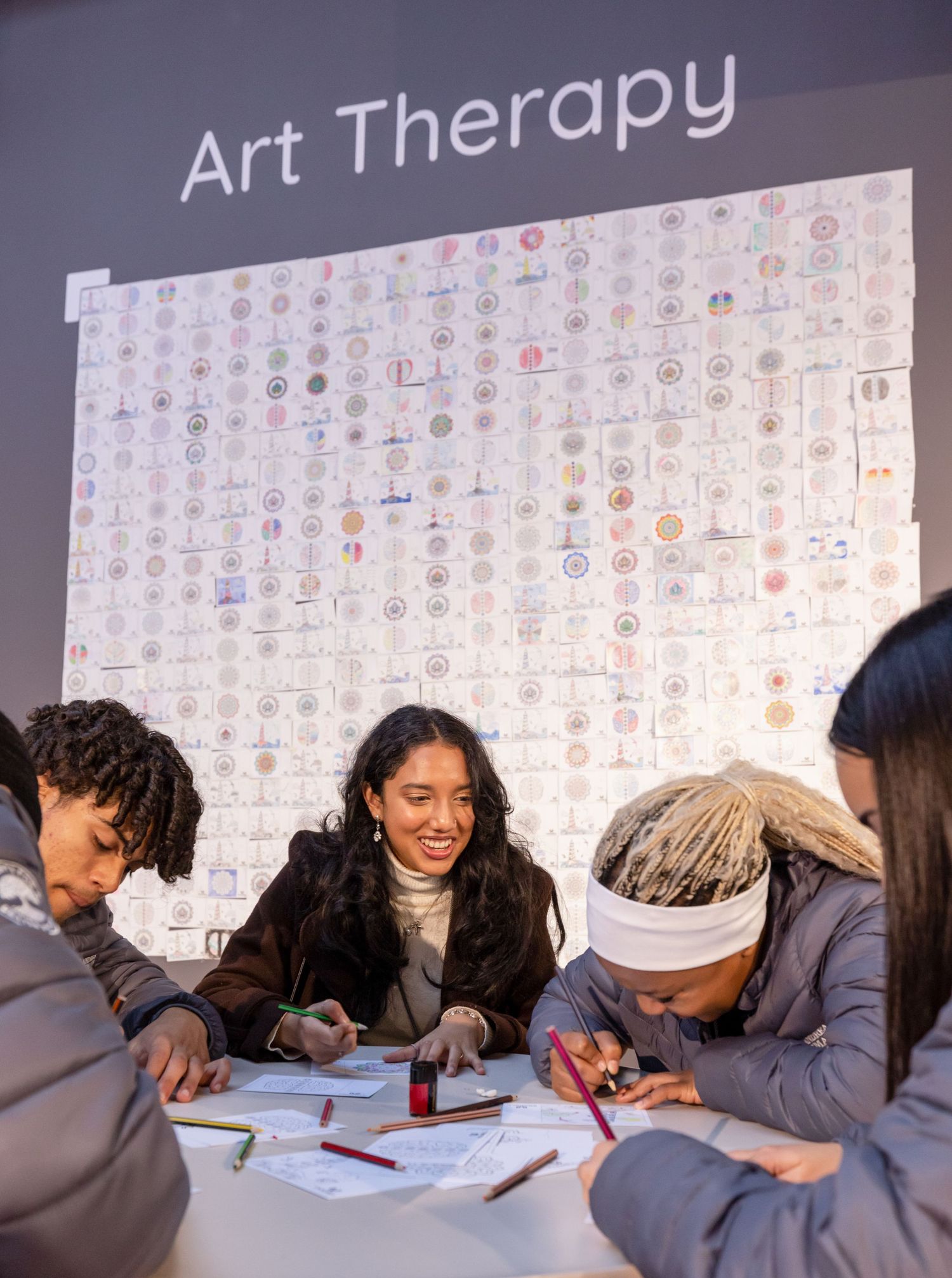 Students participate in an art therapy session while writing at a table together.