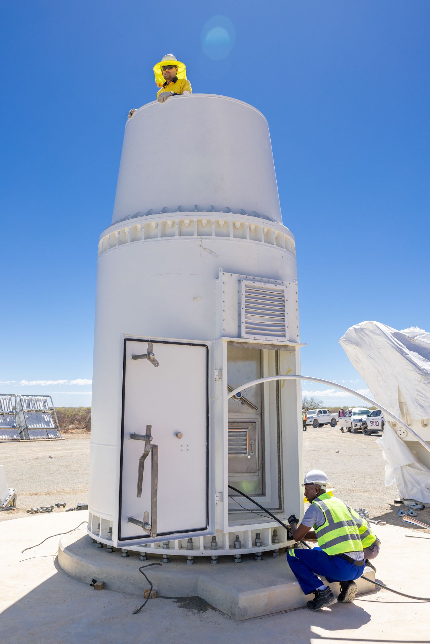 White dome-shaped structures against a bright blue sky in an arid desert landscape.