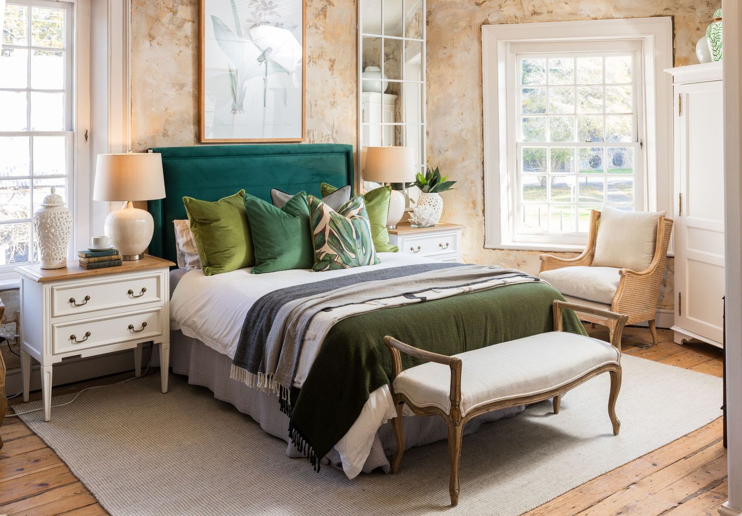 Elegant bedroom featuring emerald green headboard, white nightstands, and floral wallpaper in a bright natural setting.