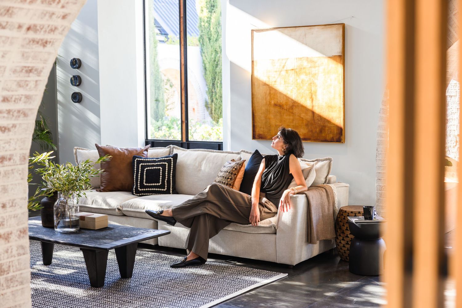 A sequence of four modern interior design photos showcasing a minimalist living space with exposed brick walls and tall windows.