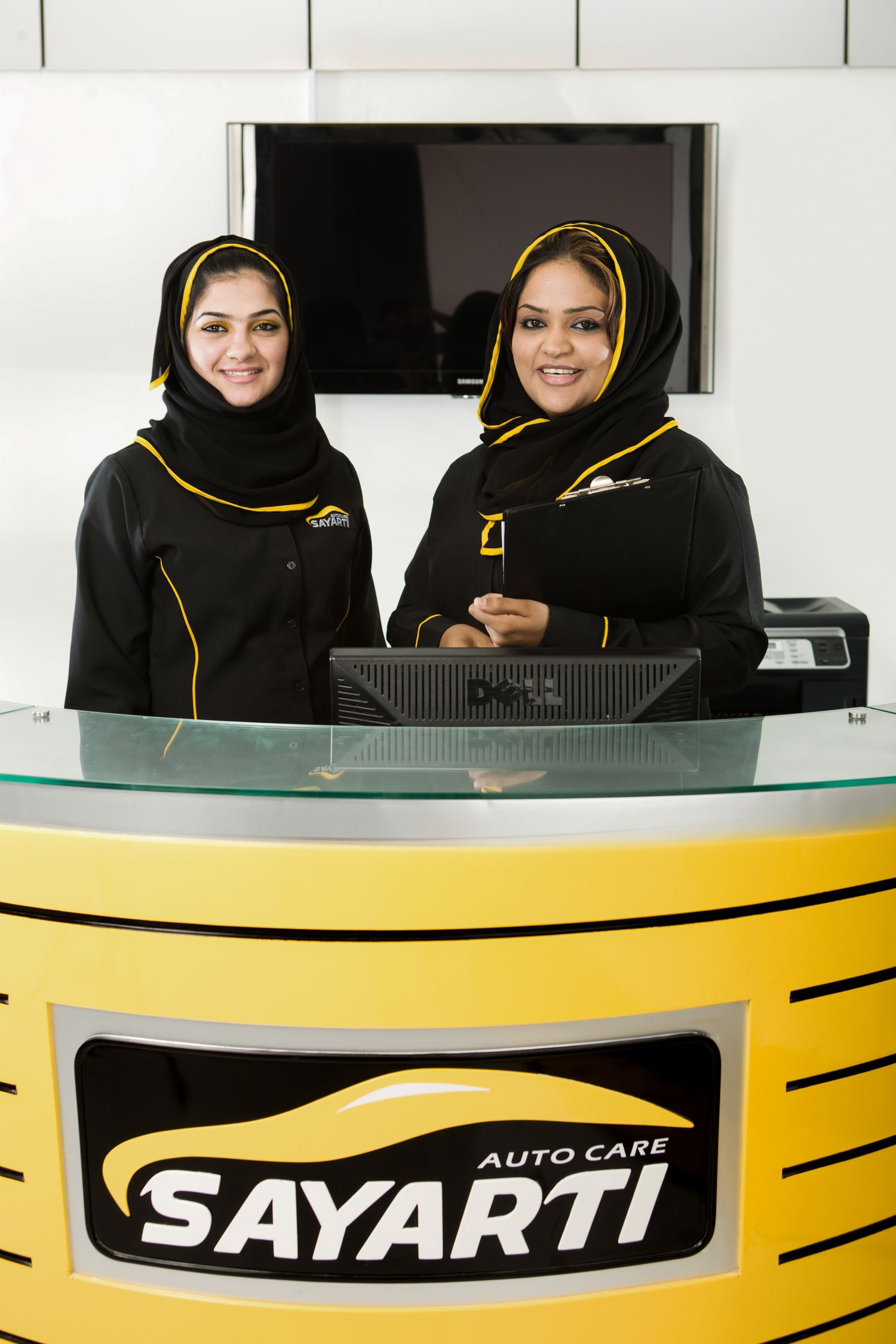 Service counter at Sayarti Auto Care featuring branded yellow and black design.