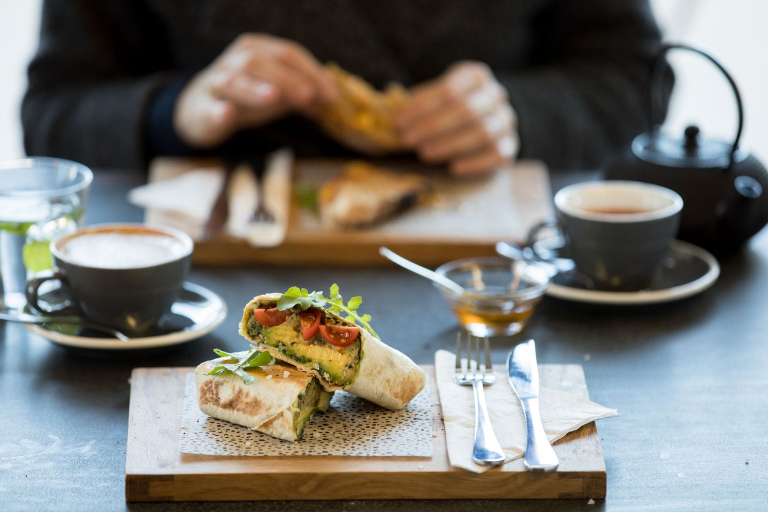 Fresh sandwiches and coffee served on wooden boards with decorative doilies at an upscale cafe.