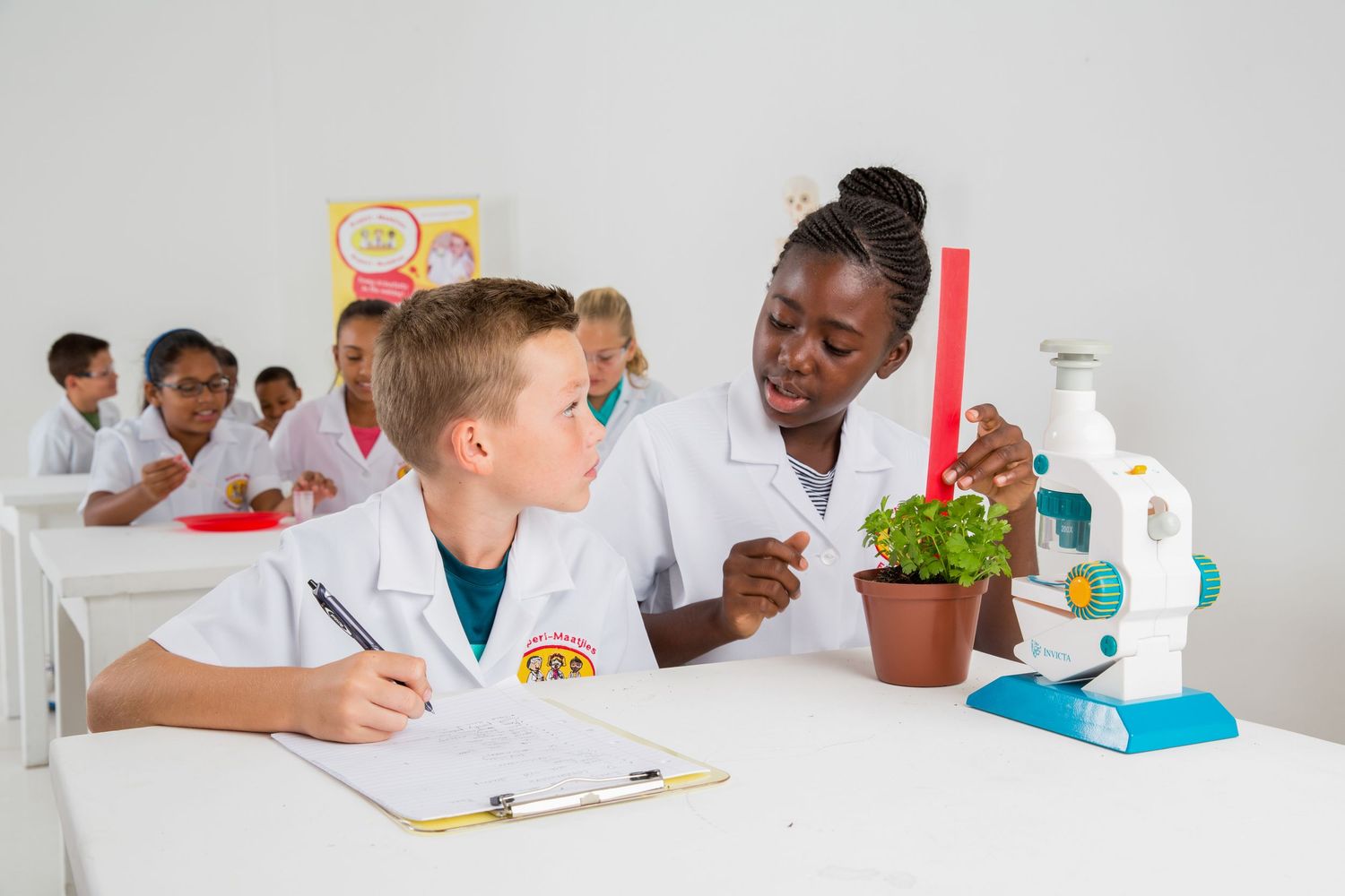 Students collaborate on microscope experiment while taking notes in science class.