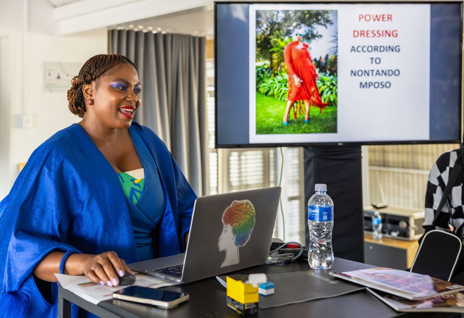 Participants work on laptops during a business workshop with presentation screens visible.