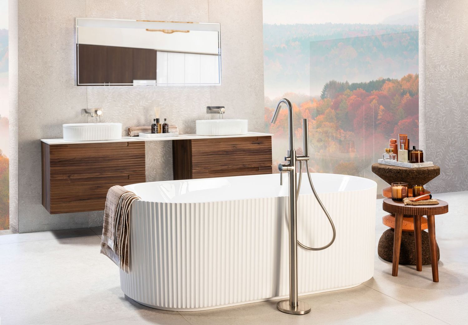 Modern bathroom interior with freestanding ribbed tub, wooden vanity, and scenic mountain wall mural in soft natural tones.