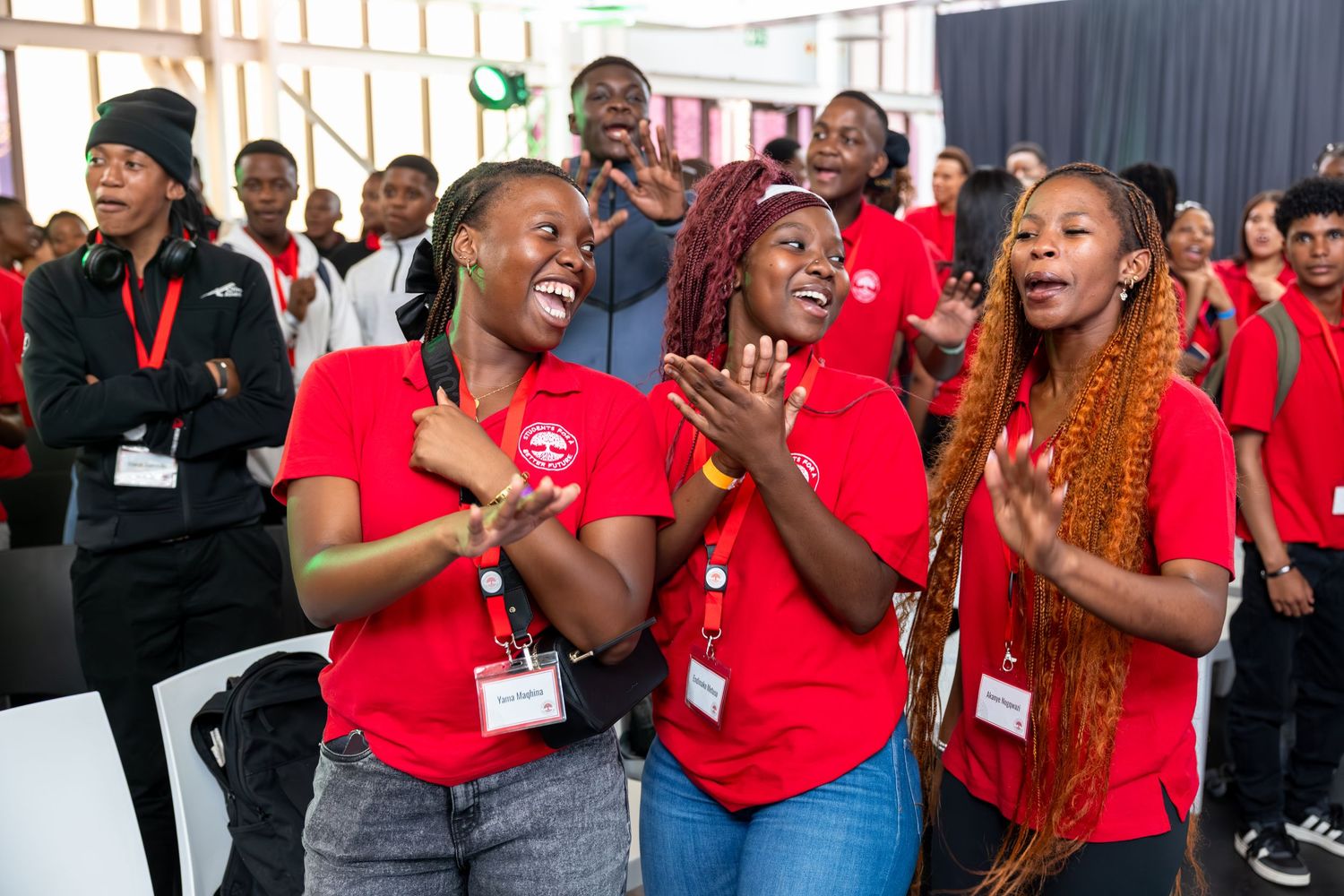 Enthusiastic conference participants in red shirts actively participating in an event session.