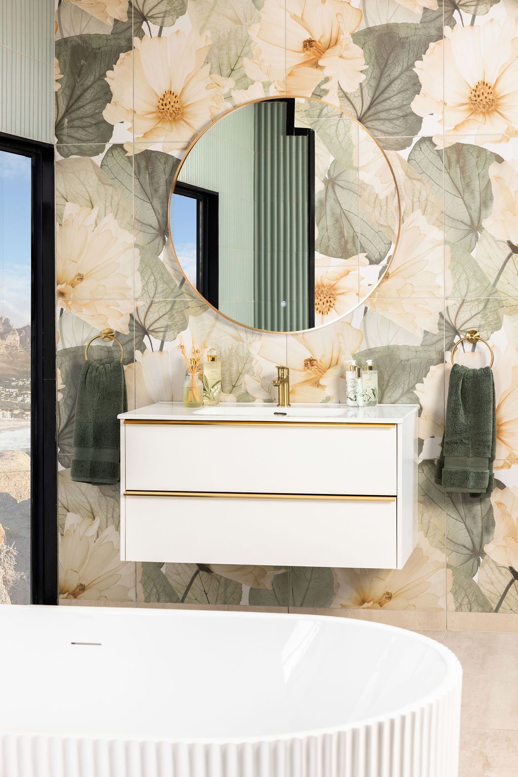 Modern bathroom interior with floral wallpaper, white floating vanity, and circular mirror against pastel walls.