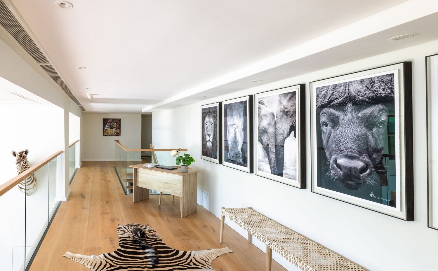 A modern minimalist white living room features large windows, wood flooring, and sleek built-in storage solutions.