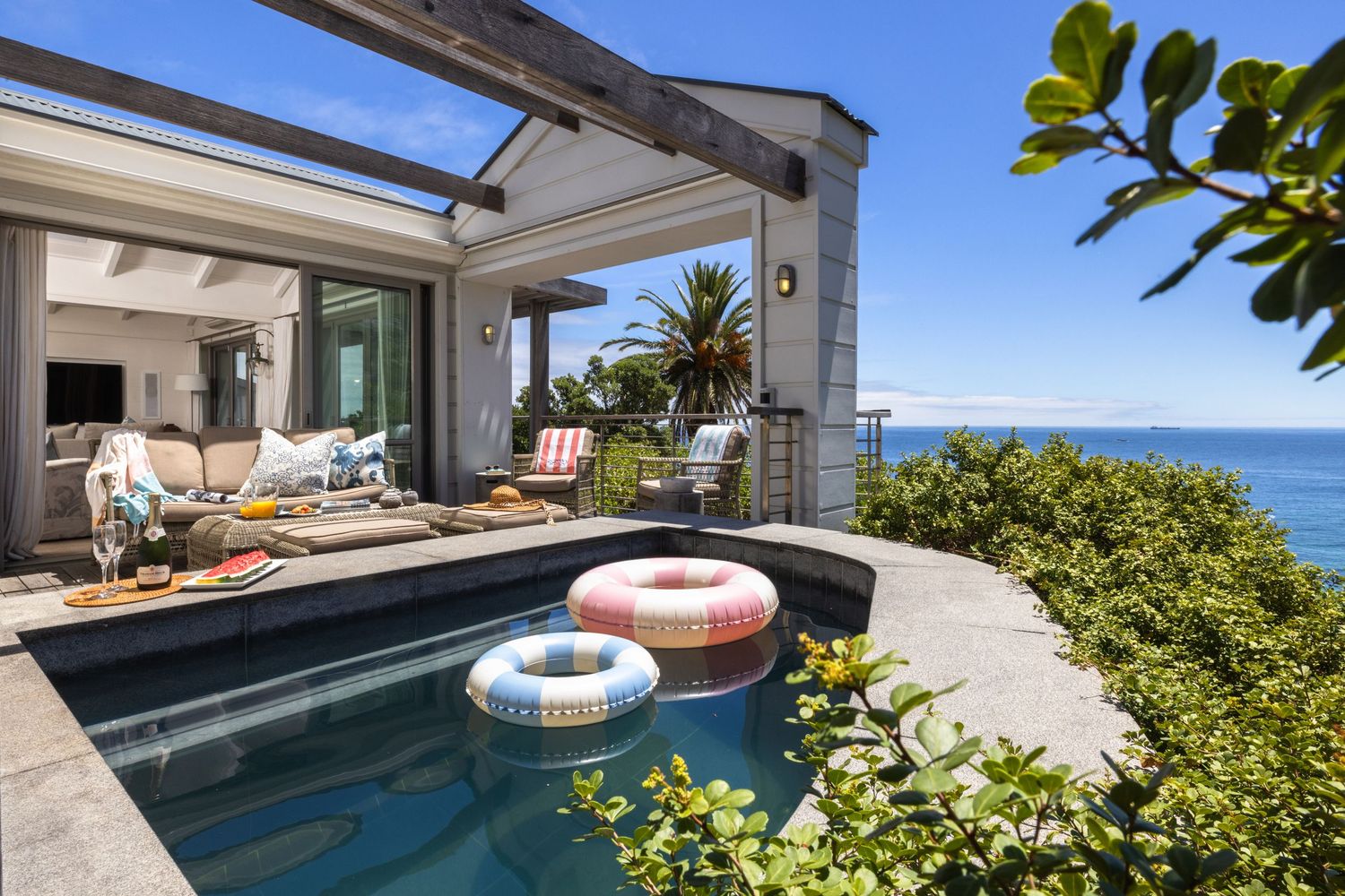Luxury beachfront property featuring an infinity pool overlooking the ocean with tropical landscaping.