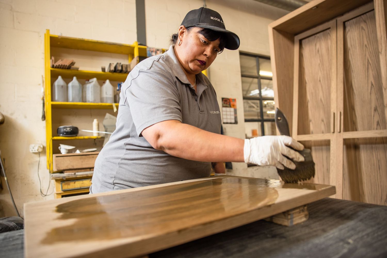 Craftsperson working on wooden cabinet assembly in manufacturing facility.