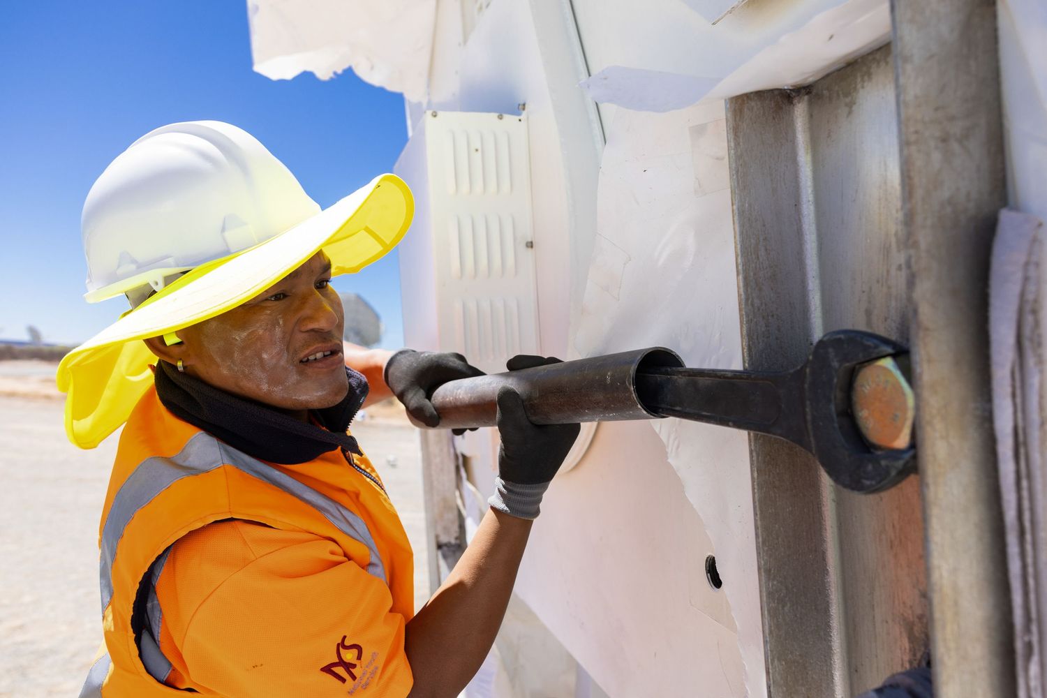 Maintenance work being performed on equipment mounted to white industrial structures.