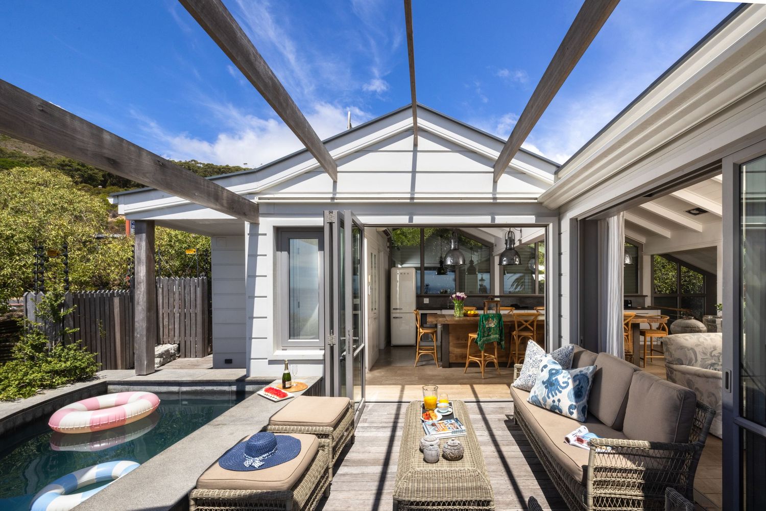 Modern backyard patio with plunge pool, outdoor seating, and glass-covered pergola connecting to contemporary home.