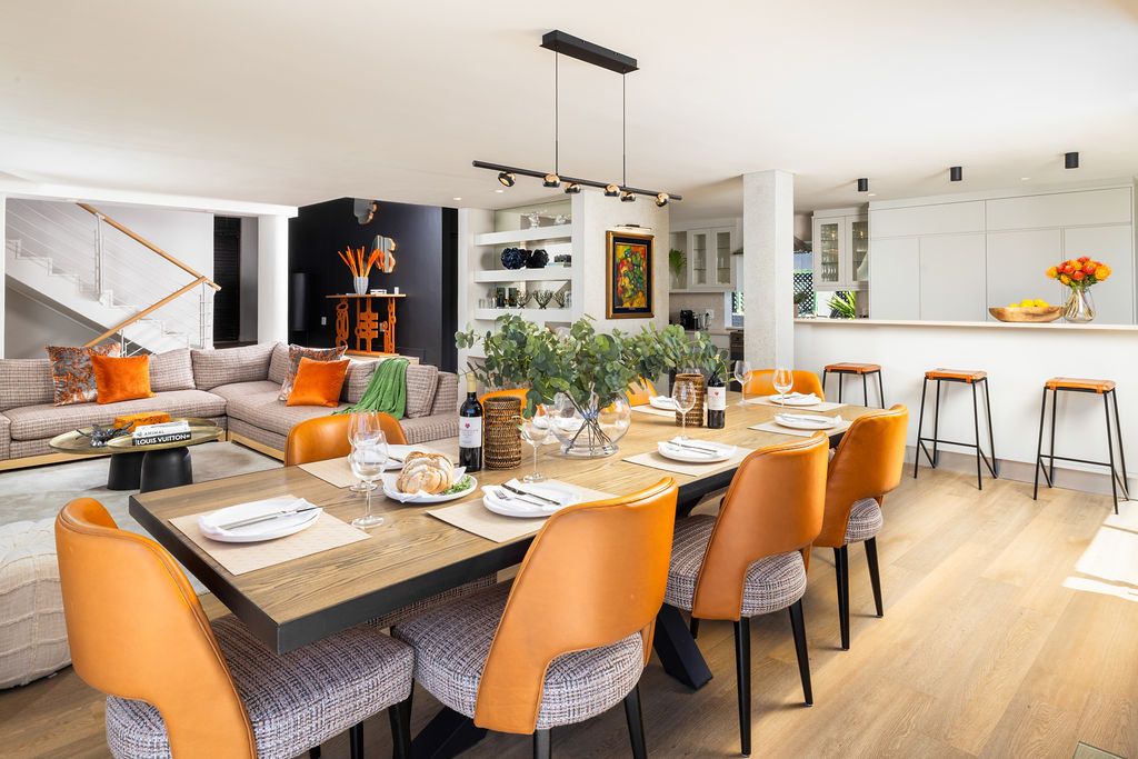 Modern dining area with orange accent chairs and gray upholstery showcases contemporary interior design elements.