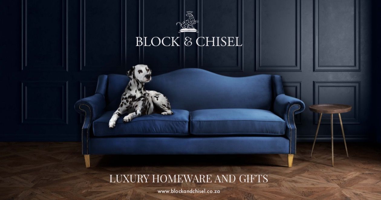 Classic navy velvet couch with natural wood side table against dark paneled wall in luxury home decor setting.
