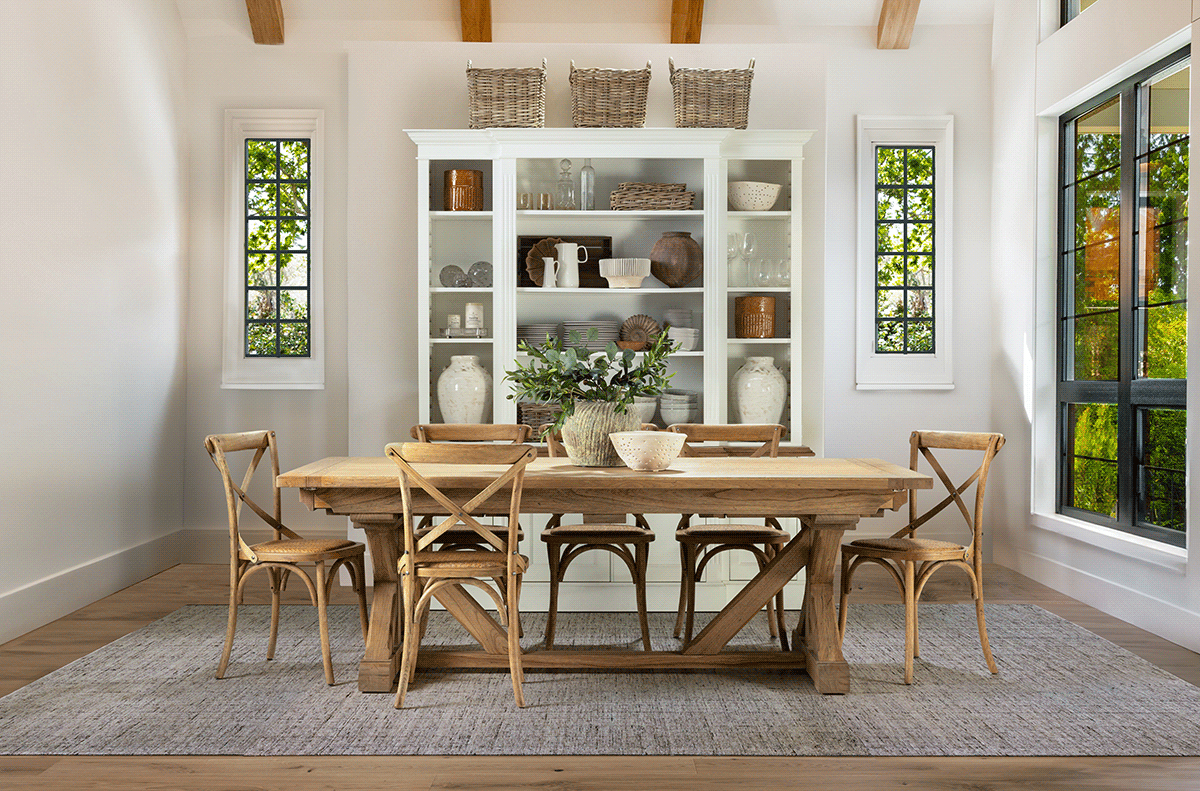 Bright dining room features farmhouse table, crossback chairs and built-in shelving with stained glass windows.