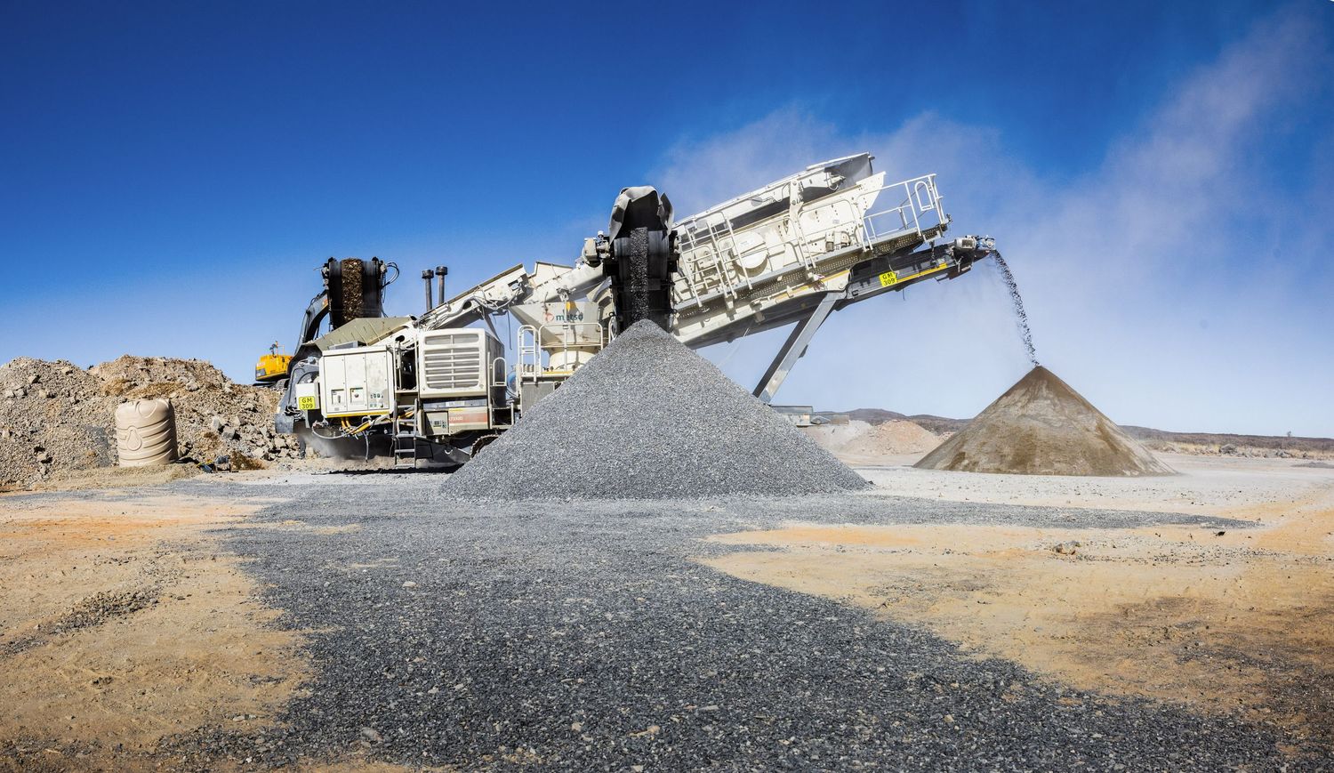Mobile crushing and screening equipment processing aggregate materials at a mining site.