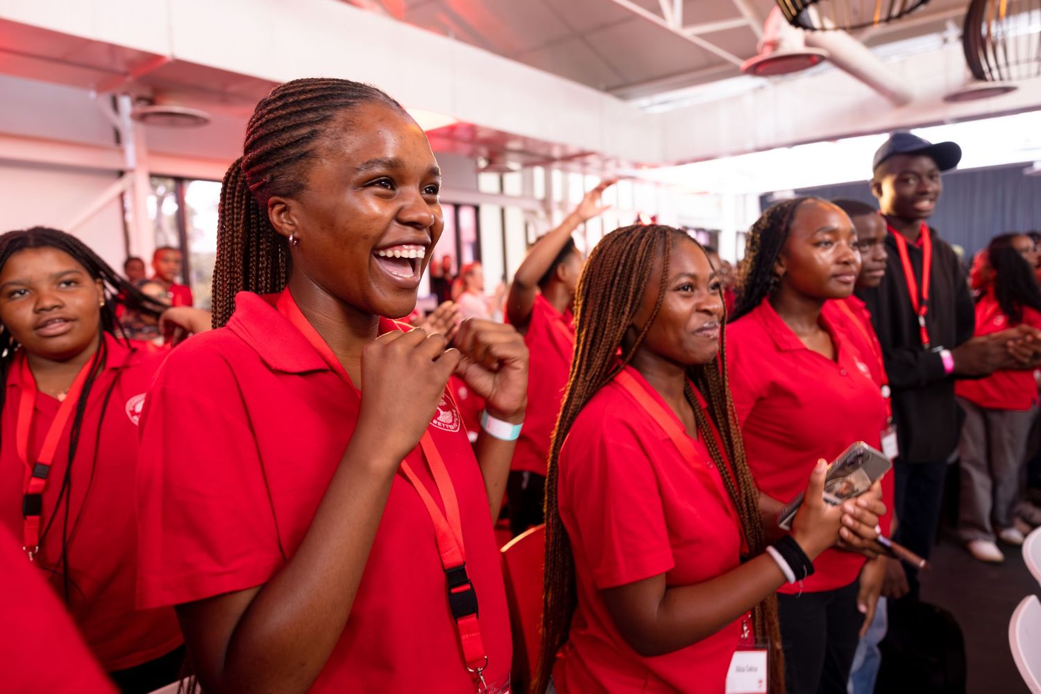 A group of participants in red shirts share an enthusiastic moment during an event.